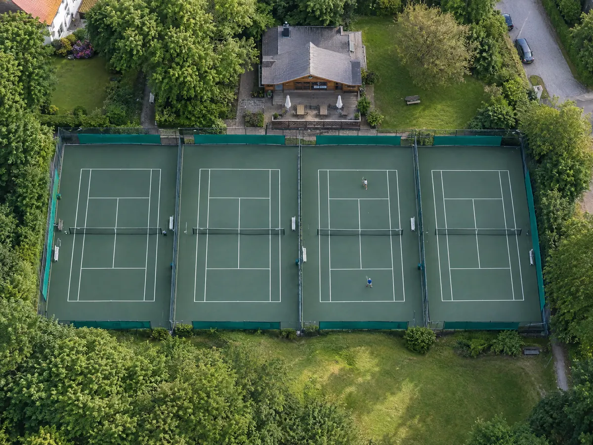Tennisanlage mit vier Plätzen und Clubhaus von oben – KI-generiertes Demobild