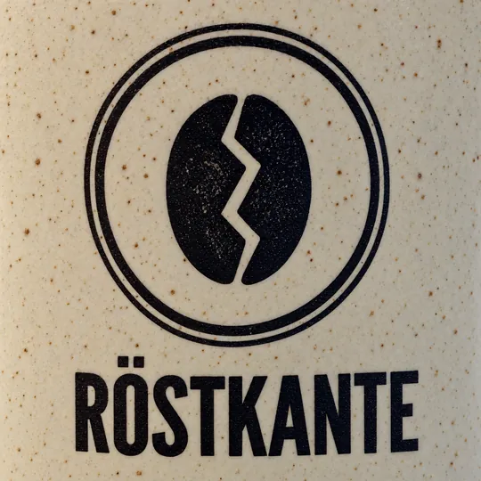 Zweiter Versuch: echte Nahaufnahme des Logos mit sichtbaren Sprenkeln der Glasur